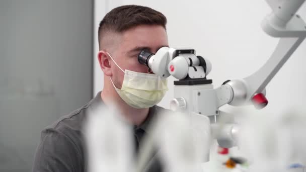 医学实验室 年轻的男性科学家对显微镜进行观察 分析疫苗样品 生物化学家开发药物 高级制药实验室的生物技术研究 — 图库视频影像