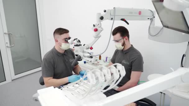 Dentista Masculino Que Trata Canais Radiculares Usando Microscópio Clínica Estomatologia — Vídeo de Stock