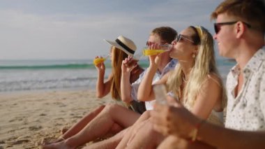 Dört neşeli arkadaş kumlu deniz sahilinde oturur, limonata içer, tropik turda kadeh kaldırır ve sohbet ederiz. İki romantik çiftten oluşan kahkaha grubu deniz kıyısında birlikte rahatlıyor. Erkek ve dişi dinlenmenin ve seyahatin tadını çıkarırlar..