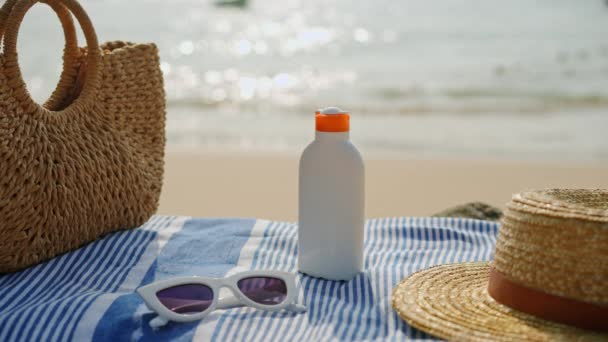 太阳镜 编织袋旁边 海滨背景 海滩必需品设置在沙滩上 防晒霜瓶与帽子关闭 紫外线保护 热带目的地的假日 护肤活动 — 图库视频影像