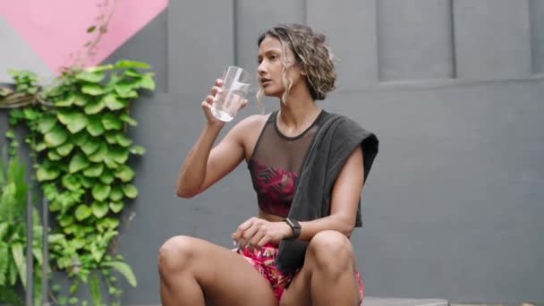 Αθλητική Γυναίκα Πίνει Νερό Αναπαύεται Στον Πάγκο Ταιριάζει Διεθνοτική Γυναίκα — Αρχείο Βίντεο