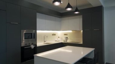 2021-10-30 - Iskele, Kuzey Kıbrıs. Cortyard Long Beach Resort Modern mutfak dairesinin içinde entegre aletler, gösterişli dolaplar, ada tezgahının ince ışıklandırması