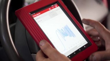 Teşhis aracı kablosuz olarak veri iletir, atölyede araba sorun çıkarır. Otomobil teknisyeni araç motor kodlarını kontrol etmek için OBD2 tarayıcı ve tablet kullanır. Mekanik hataları analiz eder, otomobil verimliliğini sağlar.