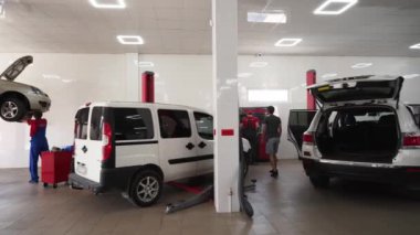 Teknisyenler arabaları tamir eder, bakım yapar, tanı koyar ve akort ederler. Otomobil tamircileri modern araba servisinin garajında araçlar üzerinde çalışırlar. Profesyonel, temiz, iyi donanımlı araç atölyesi.