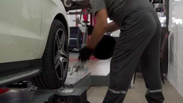 最適な運転のための専門技術サービス車の懸濁液 自動車メカニックは ガレージ内の精密機器と車輪のアライメントを調整します メンテナンス キャリブレーション 自動車ケア — ストック動画