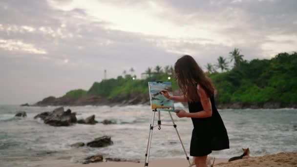 창조자는 팔레트 브러시와 작동으로 예술가는 폭풍스러운 해변의 황혼에 캔버스에 경치를 — 비디오