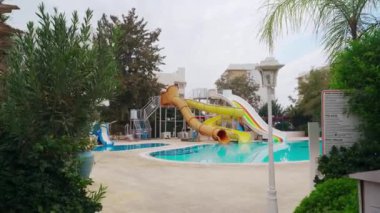 Beyaz binalar ve yeşillik potansiyeli olan yatırım arazileriyle çevrili boş yüzme havuzu.