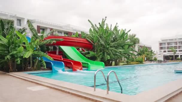 Leerer Resort Pool Mit Bunten Rutschen Umgeben Von Tropischen Pflanzen — Stockvideo