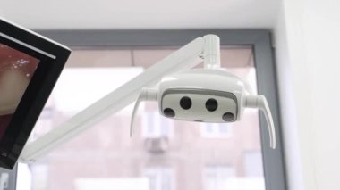 Dişçiler modern diş muayenehanesinde diş lambasını elle açarlar. Yakınlık sensörlü diş lambası. Tıp kliniğinde profesyonel modern diş aletleri. Diş sağlığı ve diş bakımı kavramı.