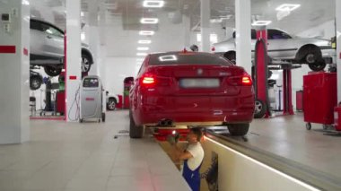 Teknisyen araç sağlığını inceliyor, gelişmiş garaj ekipmanlarını kullanarak güvenliği ve bakımı sağlıyor. Otomobil tamircisi süspansiyonu denetliyor, araba tamirhanesinde hidrolik oyun detektörü kullanıyor..