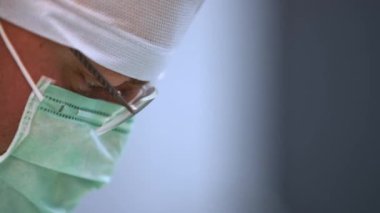 Gözlüklü dişçinin yakın çekimi, implantasyon ameliyatı sırasında yüz maskesi. Konsantre ağız cerrahı çalışıyor, diş implantı takılıyor. Modern diş sağlığı kliniğinde hasta tedavi eden erkek doktor..