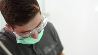 Modern diş kliniğinde kök kanallarını tedavi eden koruyucu gözlüklü beyaz erkek dişçi. Konsantre ağız cerrahı sinirleri çıkarıyor. Endodontist diş hekimini tedavi ediyor. Yakın plan..