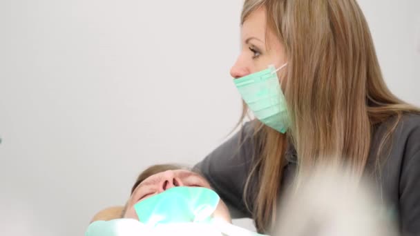 在现代牙科诊所 戴口罩的女助手与男牙医一起工作 口腔科医生在治疗病人时使用牙科器械 口腔外科准备动手术 后续行动 — 图库视频影像