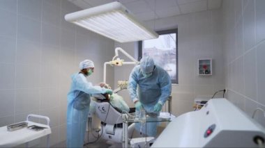 Ağız cerrahı ve asistanı modern tıp kliniğine diş implantı yerleştiriyor. Diş implantı ameliyatı, sinir ameliyatı. Dişçi ve hemşire bir hastanın kök kanallarını tedavi ediyor. Endodontikler.