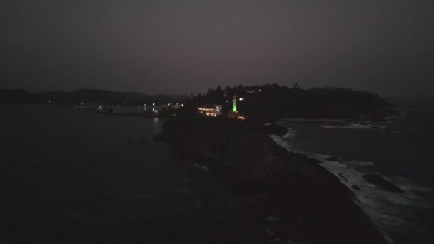 クリフサイドのトワイライトシーンは穏やかな移行 ガイド 夕暮れは岩場に衝突する波として夜に変わり 灯台は海を越え 航行のためのビーコン — ストック動画