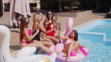 Kadınlar havuzda bikini, bikini ve bardaklarla şampanya içerler. Bayan lüks bir kulüpte şişme flamingo içip kokteyl içiyor. Güneş gözlüklü modeller rahatlar, eğlenirler..