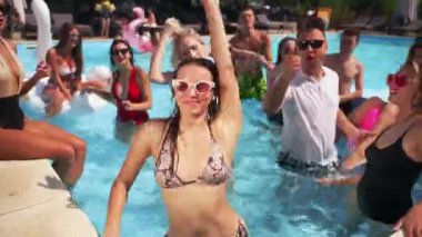 Erkek arkadaşlar ve kız arkadaşlar lüks kulüpteki havuz partisinde yaz havasının tadını çıkarıyorlar. Erkekler ve kadınlar gülümser, el sallar, dalarlar ve turkuaz berrak suda yüzerler. Arkadaşlarla sıcak tatilde gürültülü bir kutlama.
