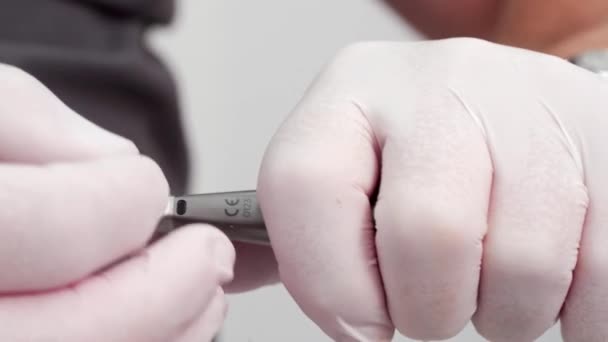 牙医手戴白色手套的特写镜头 将牙钻放入手镯内 为手术作准备 口腔外科医生在口腔科手部插入保险杠 器械和手术器械 — 图库视频影像