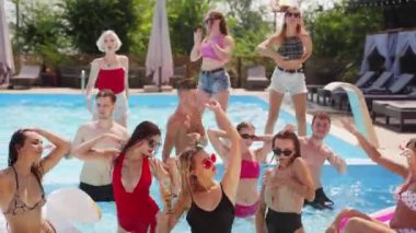 Kadın ve erkek modeller yüzme havuzunda takılıyor, su sıçratıyor, flört ediyor ve poz veriyorlar. Mayolu ve güneş gözlüklü bir grup arkadaş yaz tatillerinde eğlenir ve dinlenir..