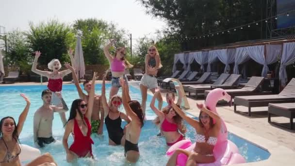 在乡村豪华俱乐部的游泳池里 热闹的夏季派对 穿着比基尼的朋友们都很开心 他们一起听音乐 喝鸡尾酒 还一起在水里享受着热假期 — 图库视频影像