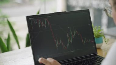 Pro tüccar, gündelik ticaretle uğraşıyor, modern ofiste hisse senedi verilerini inceliyor. Piyasa analisti dizüstü bilgisayardaki mali tabloları inceleyerek etkili yatırımların eğilimlerini analiz ediyor. İş stratejisi planı.