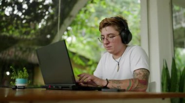 Dizüstü bilgisayardaki mürekkepli profesyonel kurgu filmleri, rahat açık ofis ortamı. Kulaklık takan transseksüel editör çalışma alanında video projesinde çalışıyor. Özel işyeri, uyarlanabilir teknoloji kullanımı.