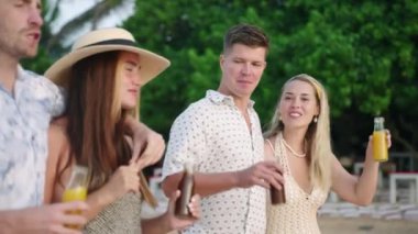 Arkadaşlar grup erkekleri, limonata şişeli kadınlar lüks plaj tatil beldelerinde içki, bardak tokuşturma, tost, sohbet, kahkaha. İki neşeli beyaz çift, güneşli bir günde eğleniyor, eğleniyor, eğleniyor, flört ediyor ve rahatlıyor..