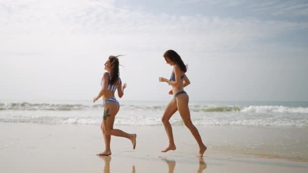 Dvě Šťastné Dívky Bikinách Běhající Vlnách Mořské Vody Veselé Kamarádky — Stock video