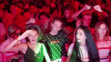 2021-08-07 - Mariupol Şehir Festivali, Ukrayna. Genç izleyiciler canlı müzikten hoşlanır, açık hava etkinliğini kutlar, yaz gece hayatını kutlar. Enerjik kalabalık gece renkli ışıklarla festival sahnesinde dans ediyor..