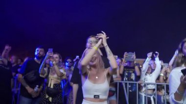 2021-08-08 - Mariupol Şehir Festivali, Ukrayna. Kalabalık gece festivalinde canlı müzik seviyor, enerjik kadınlar dans ediyor, kollarını kaldırıyor, mutlu insanlar akıllı telefonlu yaz konserleri düzenliyor..