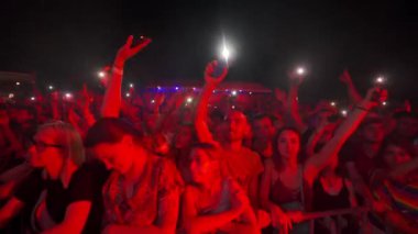 2021-08-08 - Mariupol Şehir Festivali, Ukrayna. Açık havada grup kutlaması canlı müzik etkinliği, enerji, neşe. Genç yetişkinler, gece festivalinin tadını çıkarıyorlar. Sahne ışıklarıyla aydınlatılan ellerle dans ediyorlar..