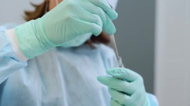 Diş cerrahisinde PRF zengin fibrin. Dişçilerin elleri tüp içinde fibrin pıhtısıyla çalışıyor. Modern diş kliniğinde trombosit zengini fibrin pıhtısı tutan doktor. PRF zar hazırlığı. Yakın plan..