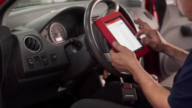 Profesyonel tamirci araba kontrolleri yapar, oto tamir hizmeti verir, araç bakımını sağlar, yazılımı yükseltir. Otomatik elektrikçi araç hatalarını tanımlamak için OBD2 tarayıcı ve tablet kullanır.