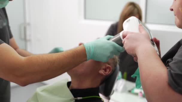 牙科医生和助手用便携式牙科X光设备拍摄颌骨X光图像 胃病医生给病人做了牙齿X光检查 数码牙科及口腔内放射科的概念 — 图库视频影像