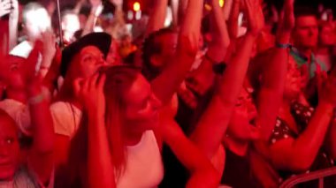 2021-08-07 - Mariupol Şehir Festivali, Ukrayna. Eller yukarı, duygular yukarı, açık havada konser. Gece müzik festivalindeki enerjik kalabalık, heyecanlı hayranlar tezahürat yapıyor, dans ediyor. Seyirci üzerindeki ışıklar canlı etkinliğin tadını çıkarıyor.