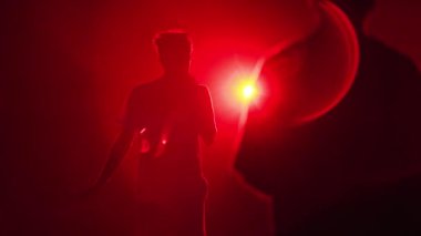 2021-08-06 - Mariupol Şehir Festivali, Ukrayna. Mikrofonlu siluetli şarkıcı konserde canlı performans sergiliyor, kırmızı sahne ışıkları kalabalığı müzik festivalinin keyfini çıkarıyor.