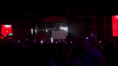 2021-08-07 - Mariupol Şehir Festivali, Ukrayna. Hayranlar canlı performansı kaydediyor, konser havasını seviyor, yaz etkinliği atmosferini seviyor. Gece müzik festivalinde kalabalık dans ediyor, kırmızı ışıklarla sahnenin önünde tezahürat yapıyor.