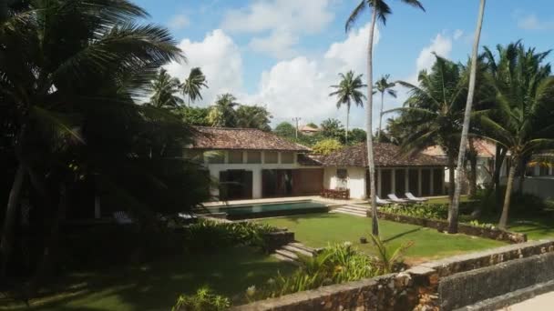 接近无人驾驶飞机拍摄的视频豪华复古别墅在海滨的岛屿 进入白色沙滩 斯里兰卡旅游胜地内有游泳池和棕榈树的别墅侧视图 — 图库视频影像