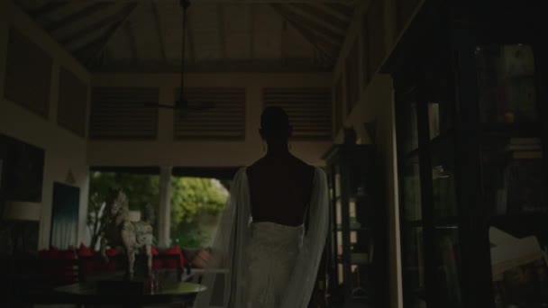 优雅的雌雄同体色彩艳丽的人在别墅里走来走去 展示他的白色连衣裙 完美的肌肤 热带岛屿房屋外拍摄的非二元黑人裸照 — 图库视频影像