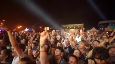 2021-08-08 - Mariupol Şehir Festivali, Ukrayna. Heyecanlı seyirciler canlı konser, açık hava etkinliği için ellerini kaldırdı. Kalabalık müzik festivali gecesi dans ediyor. Gençlik kutlaması, sahne ışıkları arka planında parti.