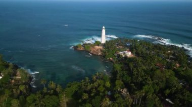 Dalgalar kayalara çarpar, kayıklar yakınlardaki sularda gezinir, dingin güzellik resim gibi kıyı şeritleri arayan gezginleri cezbeder. Dondra deniz fenerinin Sri Lanka 'da palmiye ağaçlarıyla çevrili insansız hava aracı.