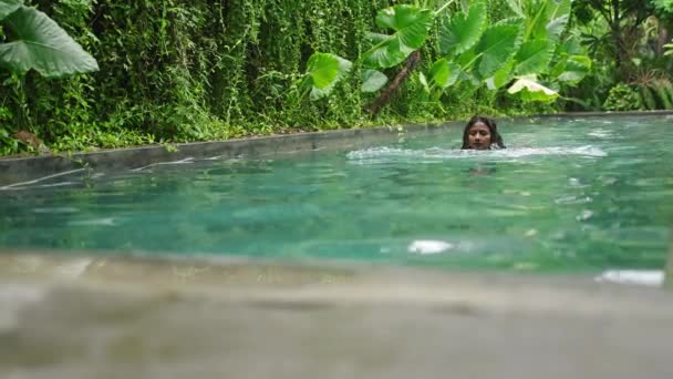 平静的游泳 清澈的水中倒影 健康的生活方式 美丽的女人在一个被绿叶环绕的热带池塘里游泳 混血的女性享受休闲 放松自然 慢动作 — 图库视频影像