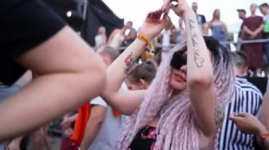 2021-08-06 - Mariupol Şehir Festivali, Ukrayna. Pembe saçlı dans eden, güneş gözlüğü takan bir kadın. Festival kalabalığı yaz müzik etkinliğinin keyfini çıkarıyor. İnsanlar parti yapar, konser havasında içerler..