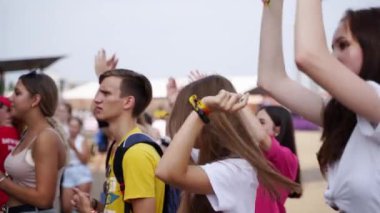 2021-08-06 - Mariupol Şehir Festivali, Ukrayna. Grup canlı müzik dinlemeyi sever, akıllı telefonlardan anları yakalar, açık gökyüzü altında yaz etkinliği havası yaratır. Genç yetişkinler dans eder, deniz kenarındaki müzik festivalinde tezahürat eder..