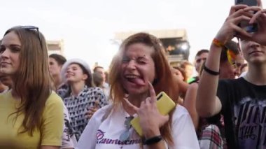 2021-08-06 - Mariupol Şehir Festivali, Ukrayna. Heyecanlı kalabalık olayları yakalıyor, deneyimleri yaşıyor. Açık hava müzik festivalindeki hayranlar konserin tadını çıkarıyorlar. Genç bir kadın gülümser, fotoğraf çeker..