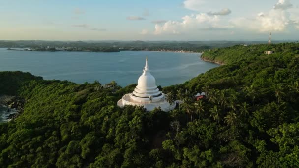 神聖なホワイトスタパは 澄んだ青い水の近く 熱帯の設定に立っています 海を見下ろす丘の上に建てられた仏教の塔の空想的な眺め 巡礼サイト スピリチュアルな旅 — ストック動画
