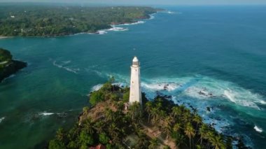 Dalgalar körfezden geçen kayalık sahil gemilerine çarpar. Tropikal adada yeşil, gök mavisi okyanus sularıyla çevrili Hollandalı deniz feneri. İHA seyrüsefer, güvenlik.