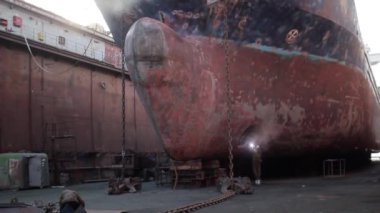 Kaynaklama, öğütme büyük gemilerin yaylarında gerçekleştirildi. İşçiler kuru rıhtımda gemi gövdesini tamir ediyorlar. Endüstriyel deniz bakımı, gemi inşa süreci ele geçirildi. Pas, tamir aletleri, tersanede görülebilir..