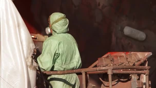 船舶维修 工业油漆 船舶维修设施防锈 船厂工人穿着防护服在干船坞的船壳上涂油漆 专业在船上使用喷枪 — 图库视频影像