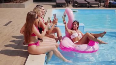 Kadınlar havuzda bikini, bikini ve bardaklarla şampanya içerler. Bayan lüks bir kulüpte şişme flamingo içip kokteyl içiyor. Güneş gözlüklü modeller rahatlar, eğlenirler..